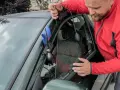 Mężczyzna używa narzędzi, aby otworzyć samochód z centralnym zamkiem. Wypompowuje powietrze, by stworzyć szczelinę.