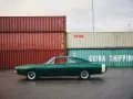 Klasyczne amerykańskie samochody, zielony Dodge Charger z lat 60. na tle kontenerów portowych.