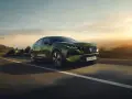 Zielony Peugeot 408 GT sunie po krętej drodze, otoczony malowniczym krajobrazem o zachodzie słońca.