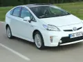 Biała Toyota Prius w ruchu. Czy warto kupić ten hybrydowy samochód?