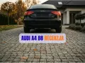 Czarny Audi A4 B8 na podjeździe przed domem. Tekst "AUDI A4 B8 RECENZJA" nałożony na obraz.