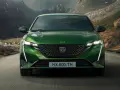 Zielony Peugeot 308 T7 jedzie drogą w malowniczym, górskim krajobrazie z widokiem na małą wioskę nad wodą.