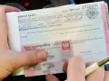 Ręka trzyma mandat karny na 300 zł i dowód osobisty. Ktoś wypełnia dokument, być może to mandat za parkowanie.