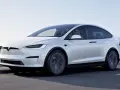Biała Tesla Model X jedzie po drodze. Zastanawiasz się, ile kosztuje Tesla Model X?