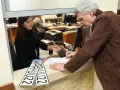 Mężczyzna składa wniosek o przerejestrowanie samochodu, podpisując dokumenty przy okienku urzędu. Obok leżą nowe tablice rejestracyjne.