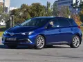 Niebieska Toyota Auris Hybrid, z kierowcą za kierownicą, na parkingu. Zastanawiasz się, ile pali Toyota Auris Hybrid?