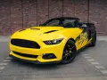 Żółty kabriolet Mustang GT 5.0 z czarnymi felgami i grafiką na boku.