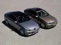 Dwa Mercedesy klasy C W204, jeden srebrny, drugi brązowy, stoją obok siebie na żwirowym placu.