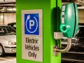 Znak "Tylko pojazdy elektryczne" i zielona ładowarka EVbox. Zastanawiasz się, ile kosztuje ładowanie samochodu elektrycznego w domu?