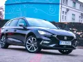 Czarny Seat Leon Sportstourer z polskimi tablicami rejestracyjnymi stoi na brukowanym placu przed budynkiem z niebieską, ozdobną ścianą.