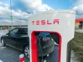 Czarna Tesla podłączona do ładowarki. Zastanawiasz się, ile kosztuje ładowanie Tesli? To zależy od taryfy i lokalizacji.