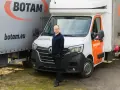 Mężczyzna stoi przed białym busem do transportu międzynarodowego marki BOTAM.
