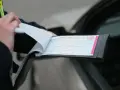 Policjant wypisuje mandat za kolizję. Dokument zawiera numer seryjny i pieczęć.
