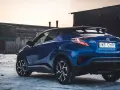 Niebieska Toyota C-HR Hybrid na tle opuszczonych budynków. Czy wybrać hybrydę czy benzynę?