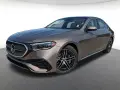 Elegancki brązowy Mercedes-Benz E450 sedan z czarnymi felgami stoi na szarym podłożu.
