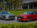 Dwa nowe Fordy Mondeo mk6, jeden czerwony, drugi szary, stoją obok siebie na tle nowoczesnego budynku i zieleni.