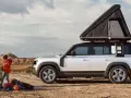 Rodzina przygotowuje się do biwaku z jednym z najbardziej polecanych samochodów 7-osobowych, wyposażonym w namiot dachowy, w surowym, pustynnym krajobrazie.
