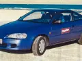 Niebieski Toyota Paseo stoi na plaży, z morzem w tle.