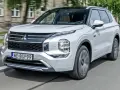 Biały Mitsubishi Outlander PHEV, jeden z nowoczesnych modeli tej marki, jedzie po mieście.