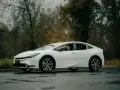 Biała Toyota Prius na mokrej drodze. Zastanawiasz się, ile wytrzymuje bateria w hybrydzie Toyoty?