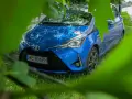 Niebieski Toyota Yaris Hybrid. Czy warto? Zobacz auto z bliska, ukryte wśród zieleni.