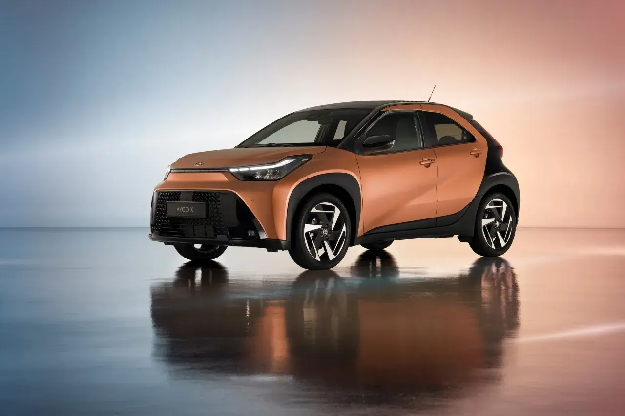 Pomarańczowa Toyota Aygo X z czarnymi dodatkami, idealna do miasta. Sprawdź atrakcyjną toyota hybryda cena.