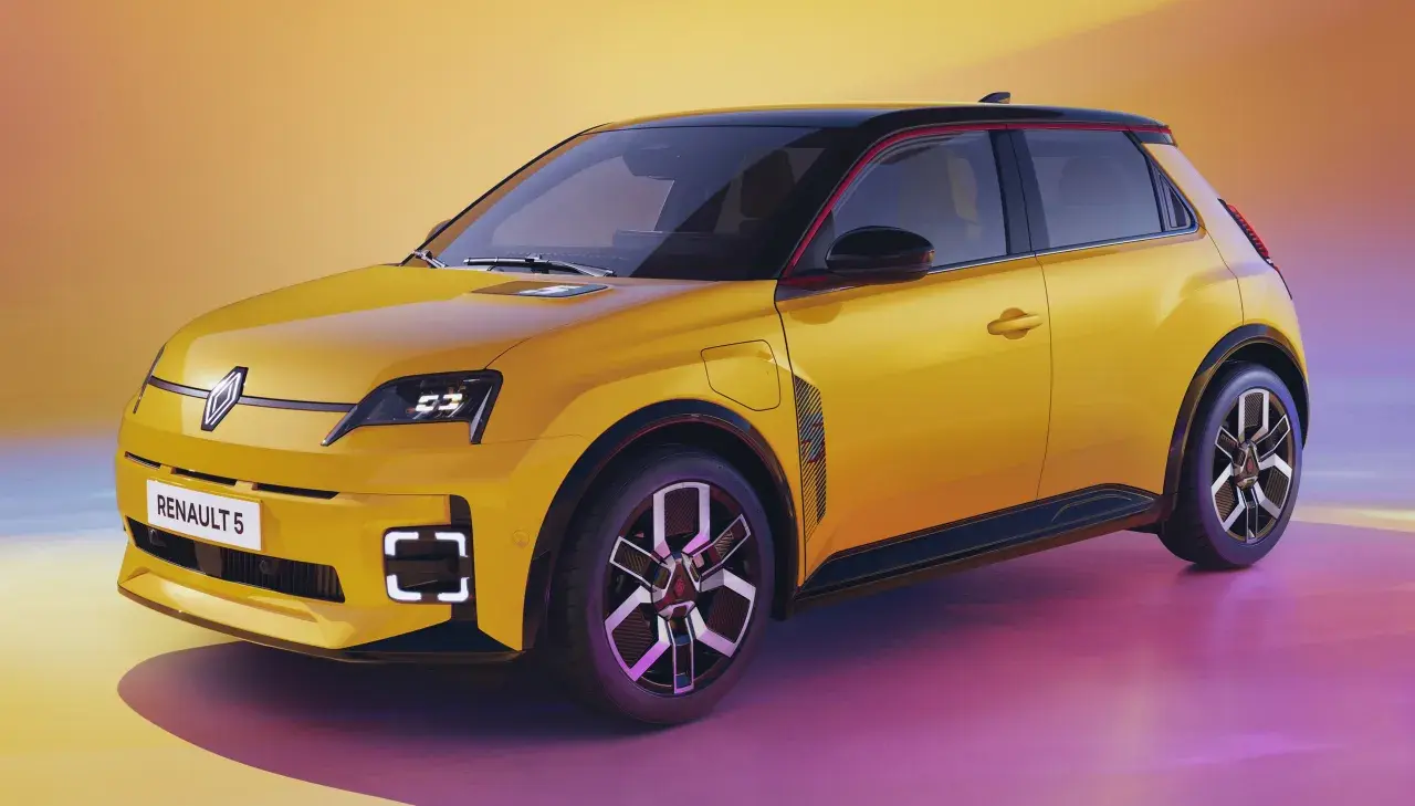 Nowy, żółty Renault 5 z czarnym dachem i czerwonymi akcentami, prezentuje nowoczesny design.