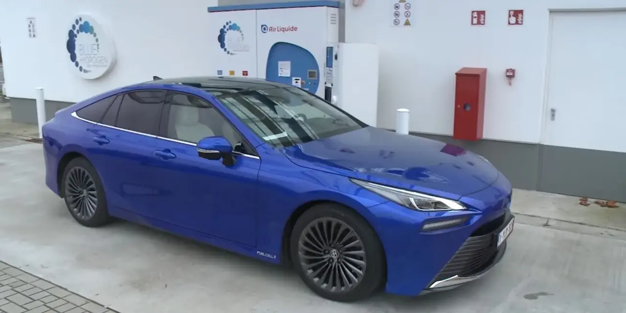 Niebieska Toyota Mirai na stacji wodorowej. Zastanawiasz się nad toyota mirai cena?