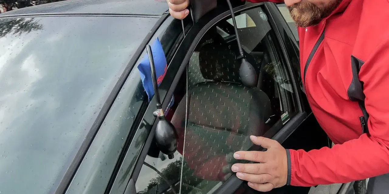 Mężczyzna używa narzędzi, aby otworzyć samochód z centralnym zamkiem. Wypompowuje powietrze, by stworzyć szczelinę.