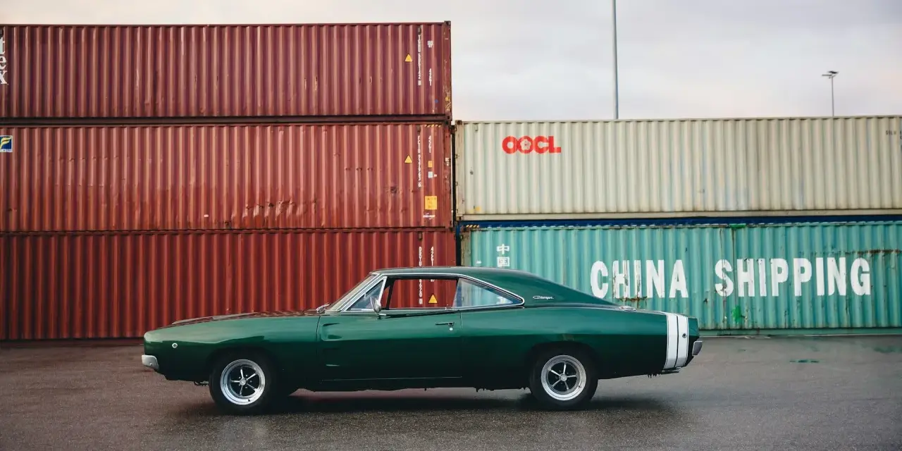 Klasyczne amerykańskie samochody, zielony Dodge Charger z lat 60. na tle kontenerów portowych.