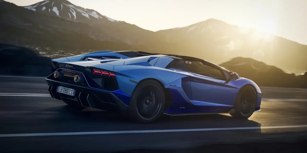Niebieski Lamborghini Aventador pędzi po górskiej drodze. Choć trudno określić, ile pali Lamborghini Aventador, jego moc jest niezaprzeczalna.