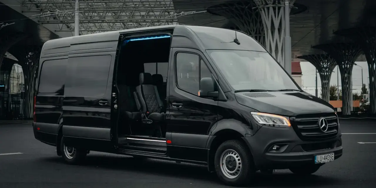 Czarny Mercedes Sprinter z otwartymi drzwiami, wnętrze z wygodnymi fotelami. Zastanawiasz się, ile kosztuje bus do Francji?