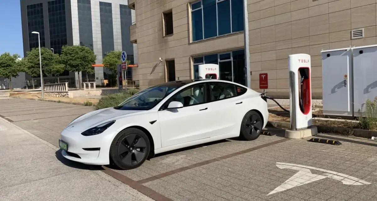 Biały Tesla Model 3, zasilany energią, czeka na ładowanie. Zastanawiasz się, ile koni ma ten model?