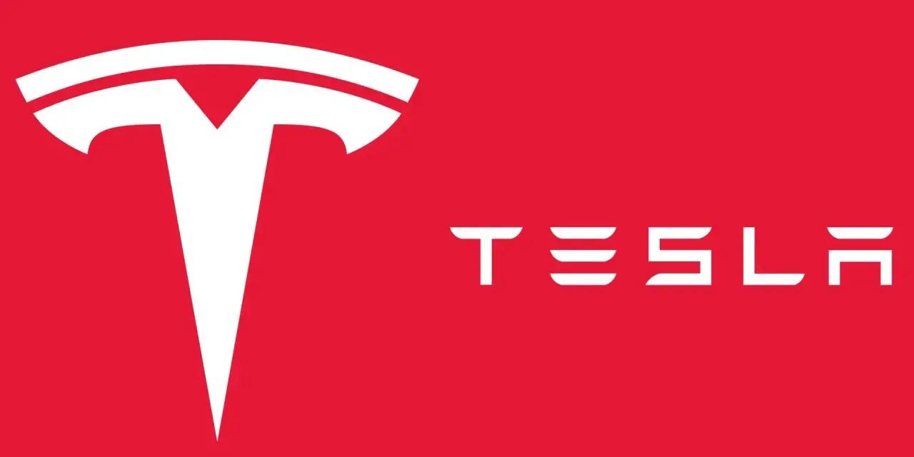 Biały, stylizowany symbol litery "T" i napis "TESLA" na czerwonym tle. Tak wygląda znaczek Tesli.