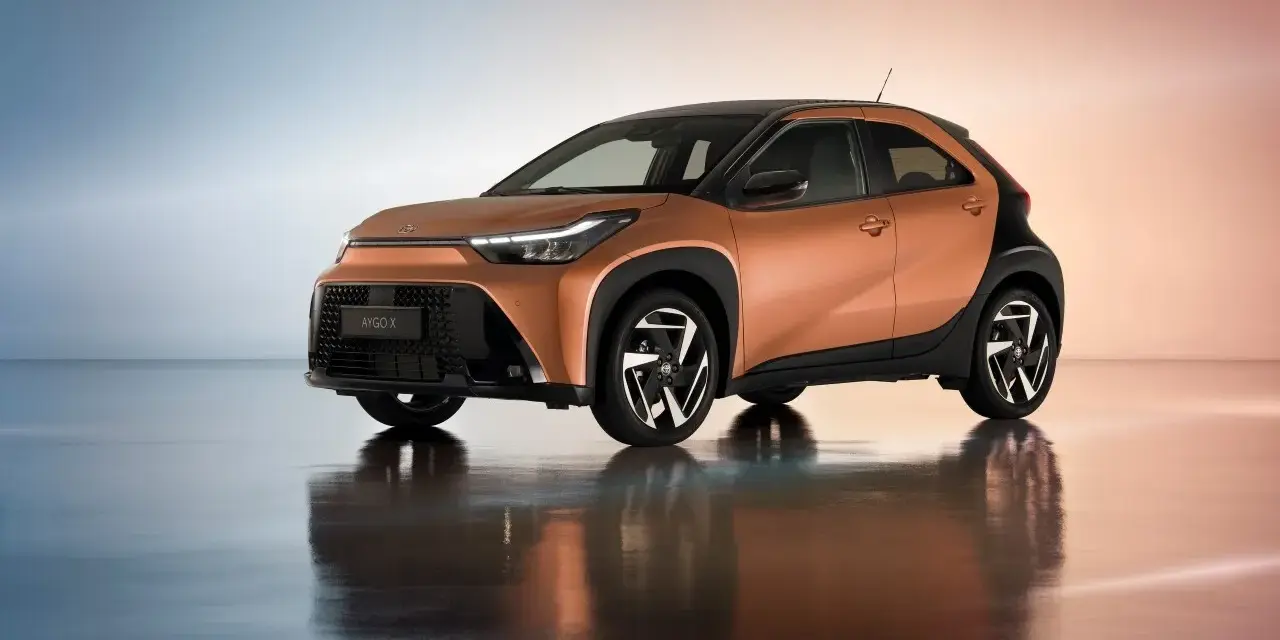 Pomarańczowa Toyota Aygo X z czarnymi dodatkami, idealna do miasta. Sprawdź atrakcyjną toyota hybryda cena.