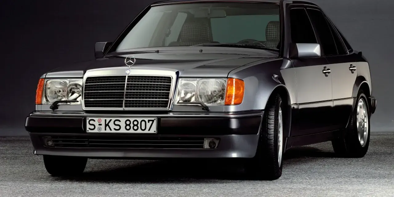 Klasyczny youngtimer, szary Mercedes-Benz W124 z charakterystyczną kratką i reflektorami.