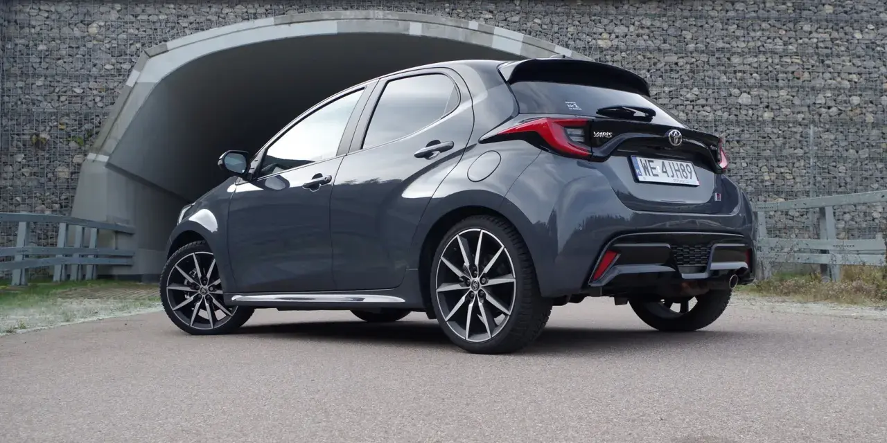 Szary Toyota Yaris Hybrid stoi przed tunelem. Dowiedz się, ile pali Toyota Yaris Hybrid, analizując jego osiągi.