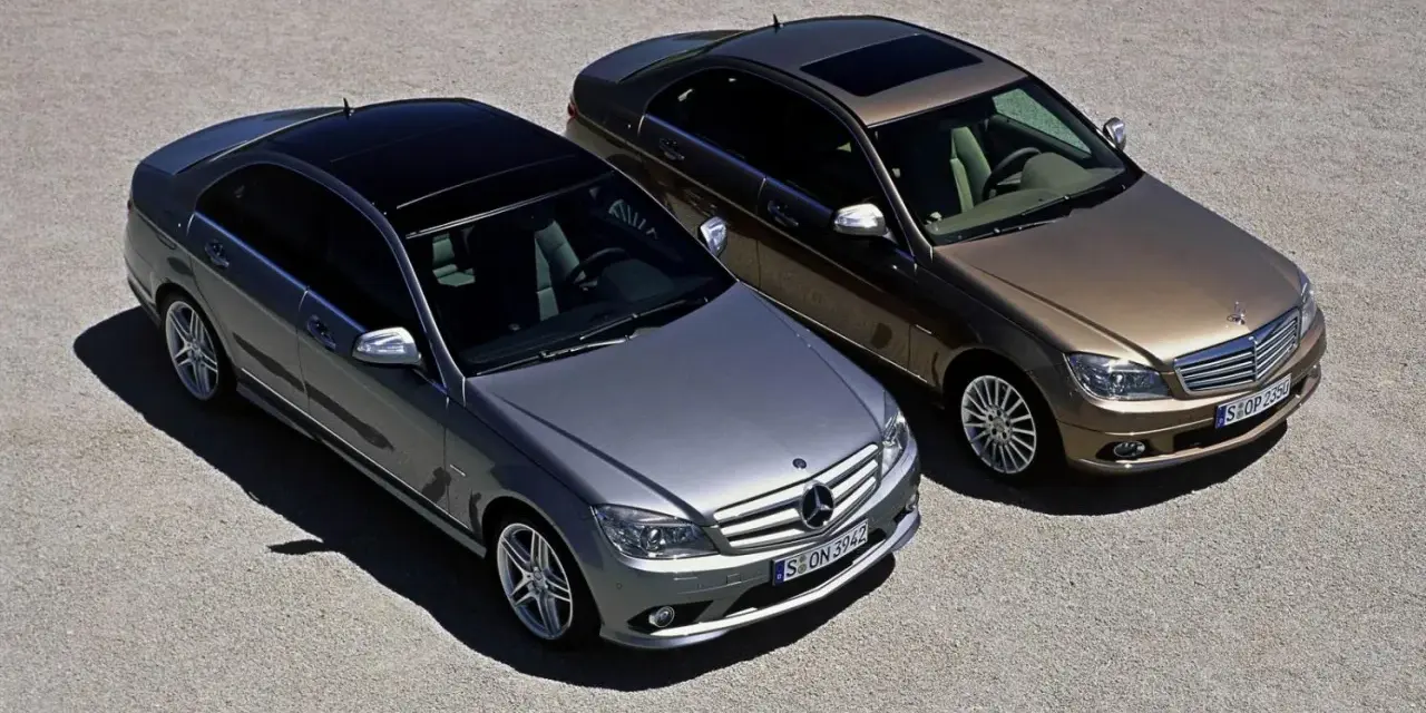 Dwa Mercedesy klasy C W204, jeden srebrny, drugi brązowy, stoją obok siebie na żwirowym placu.