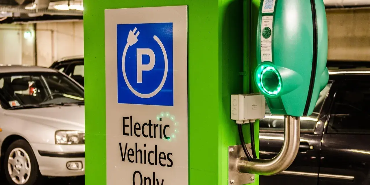 Znak "Tylko pojazdy elektryczne" i zielona ładowarka EVbox. Zastanawiasz się, ile kosztuje ładowanie samochodu elektrycznego w domu?
