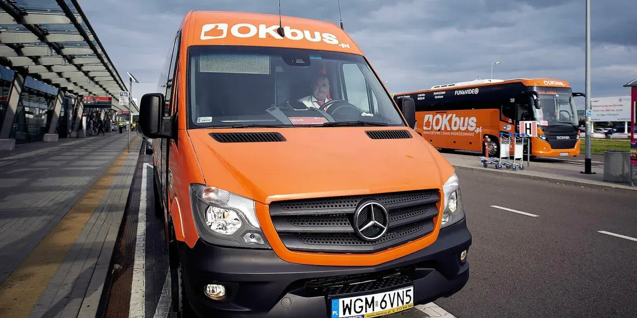 Pomarańczowy bus OKBUS czeka na pasażerów. Zastanawiasz się, ile kosztuje bus z Łodzi do Uniejowa? Sprawdź ofertę przewoźnika.