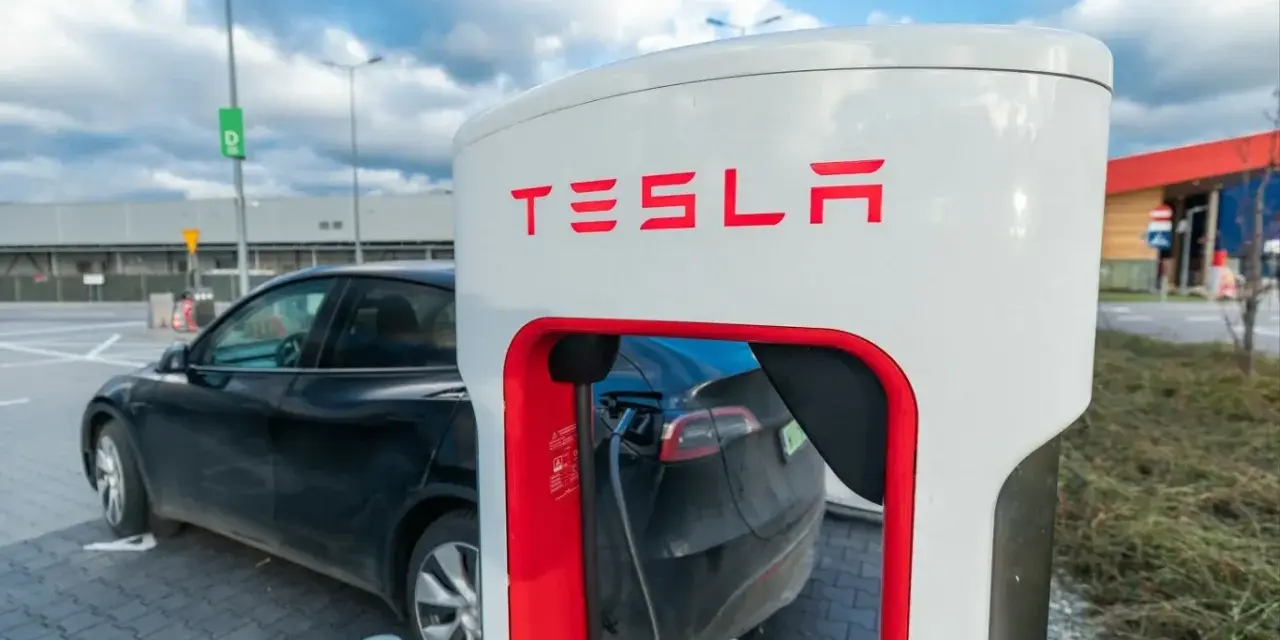 Czarna Tesla podłączona do ładowarki. Zastanawiasz się, ile kosztuje ładowanie Tesli? To zależy od taryfy i lokalizacji.