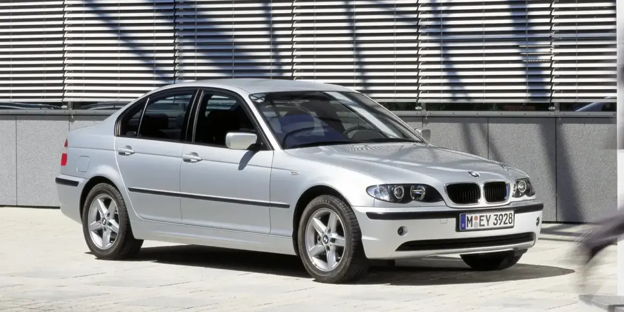 Srebrne e46 bmw sedan stoi przed nowoczesnym budynkiem z żaluzjami.