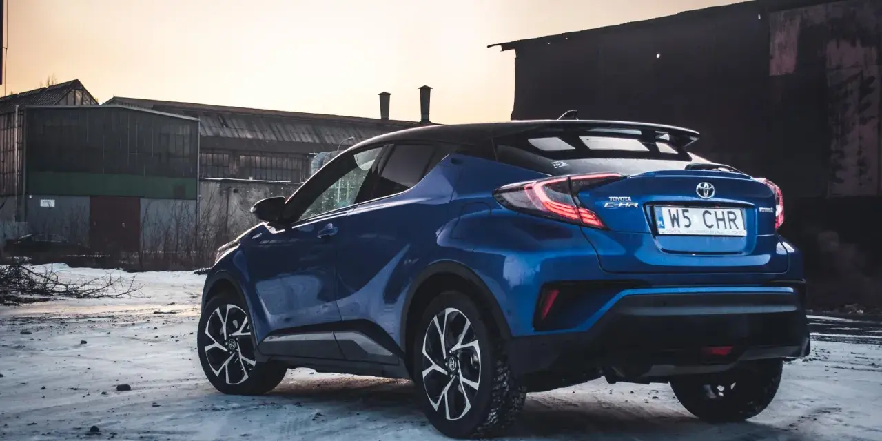 Niebieska Toyota C-HR Hybrid na tle opuszczonych budynków. Czy wybrać hybrydę czy benzynę?