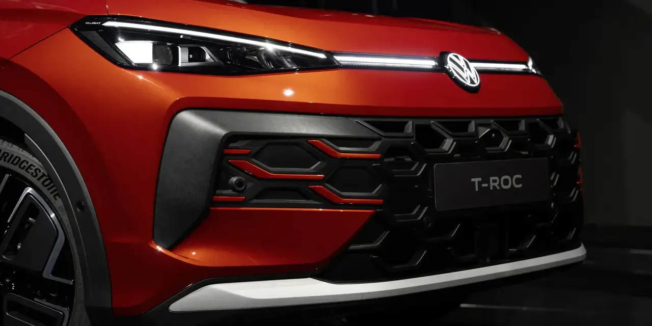 Nowy VW T-Roc w kolorze pomarańczowym prezentuje się z przodu z charakterystycznym grillem i nowoczesnymi światłami IQ.LIGHT.