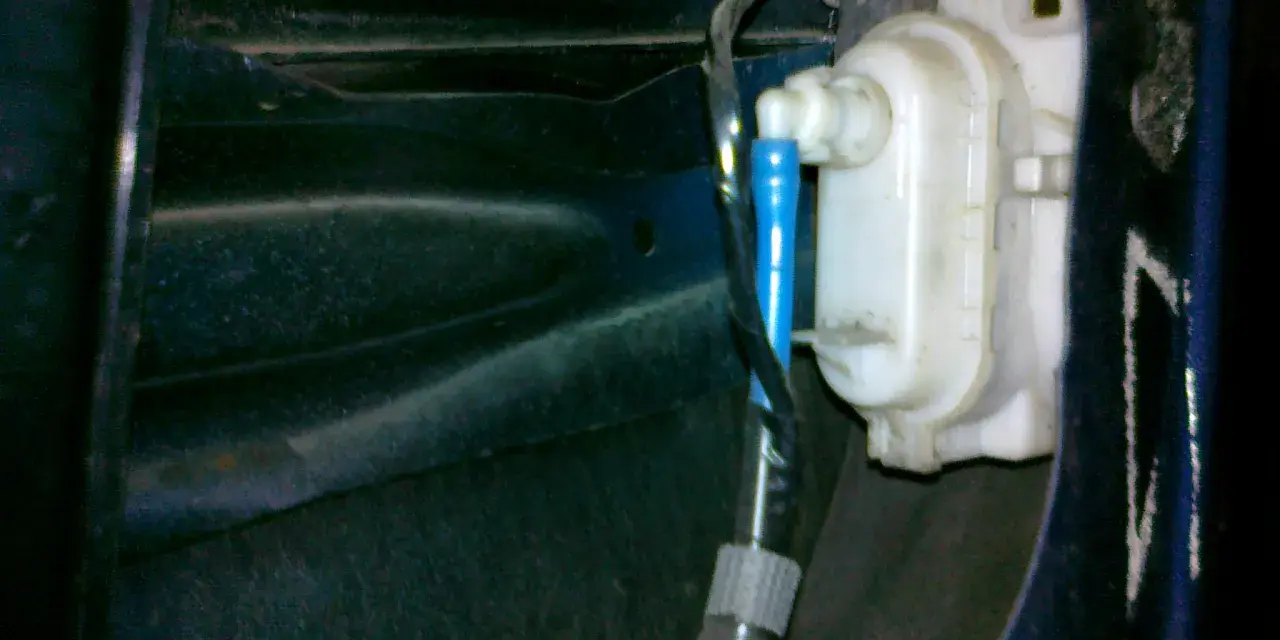 Mechanizm zamka w drzwiach VW Polo. Widoczny siłownik i przewody, pomocne przy pytaniu jak zamontować centralny zamek VW Polo.
