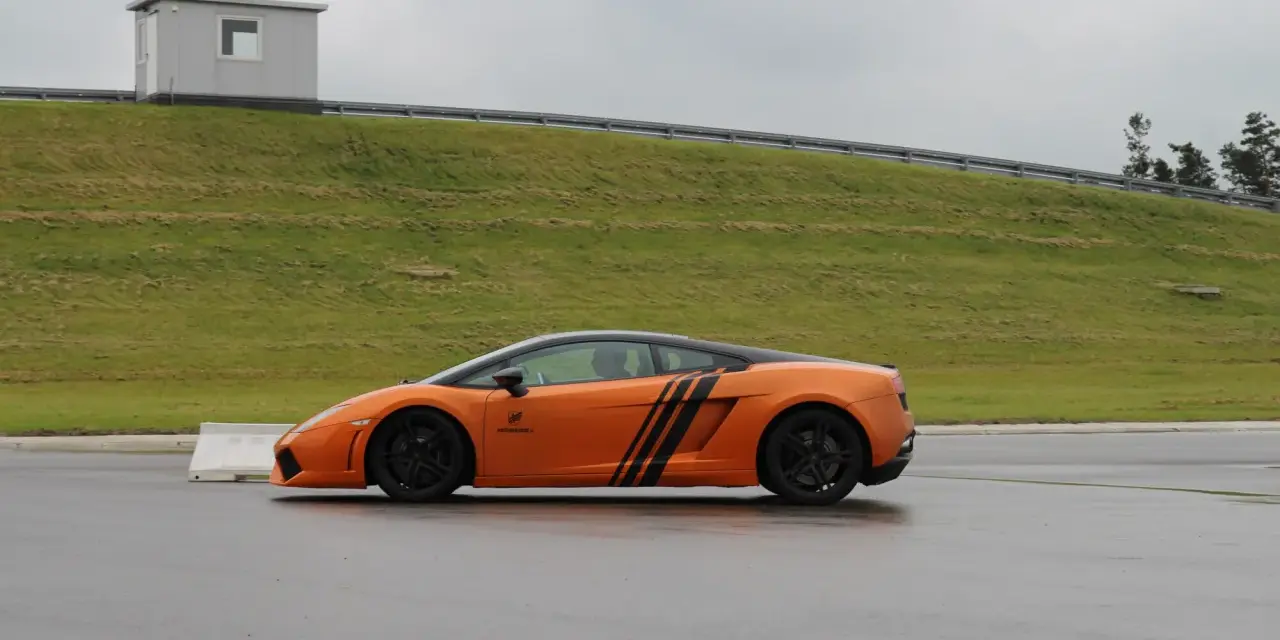 Pomarańczowe Lamborghini na torze. Zastanawiasz się, ile kosztuje przejazd takim autem?