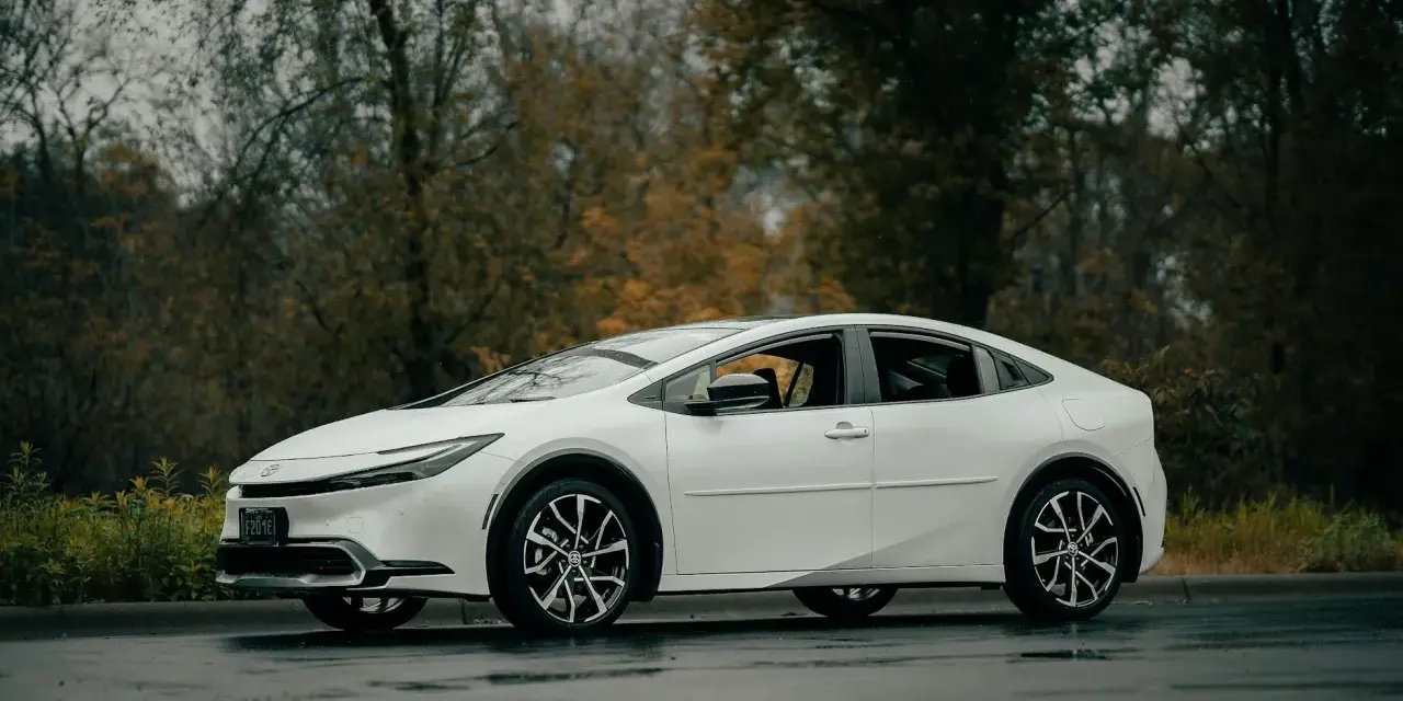 Biała Toyota Prius na mokrej drodze. Zastanawiasz się, ile wytrzymuje bateria w hybrydzie Toyoty?
