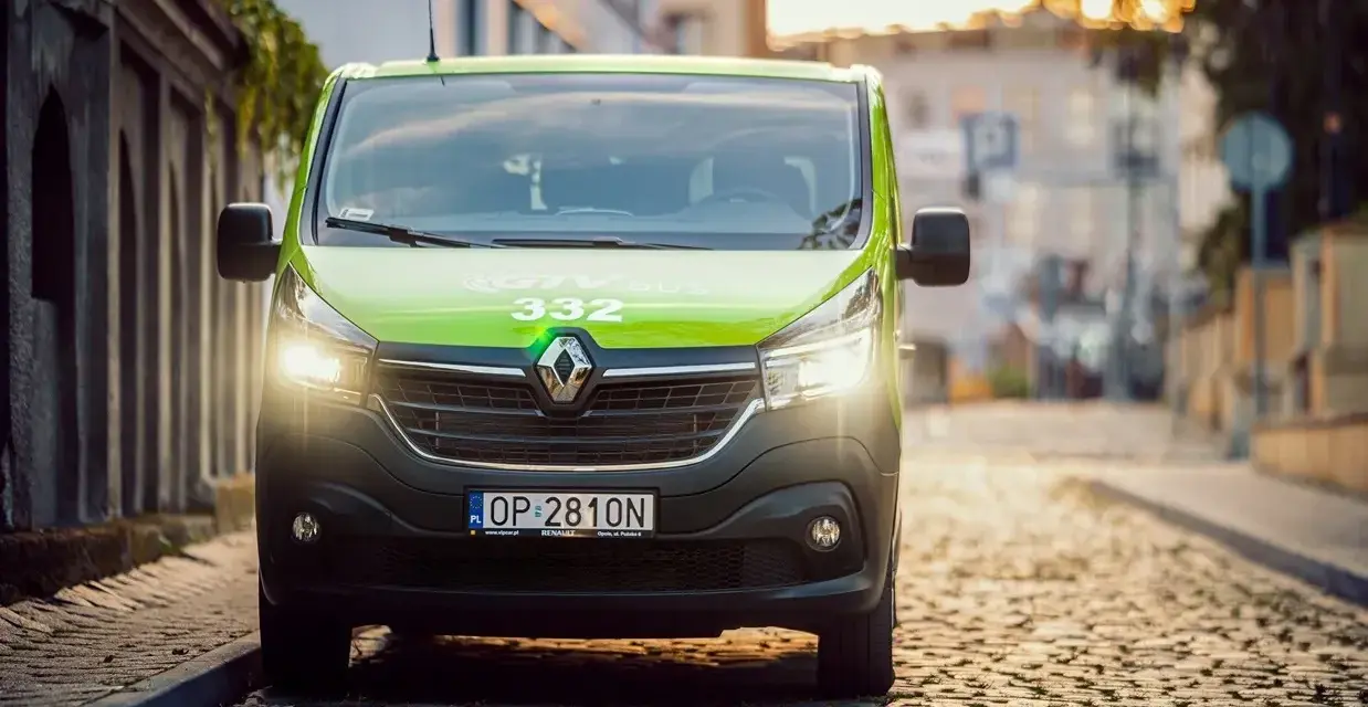 Zielony bus GTV BUS 332 na brukowanej ulicy. Sprawdź, ile kosztuje bus z adresu pod adres.