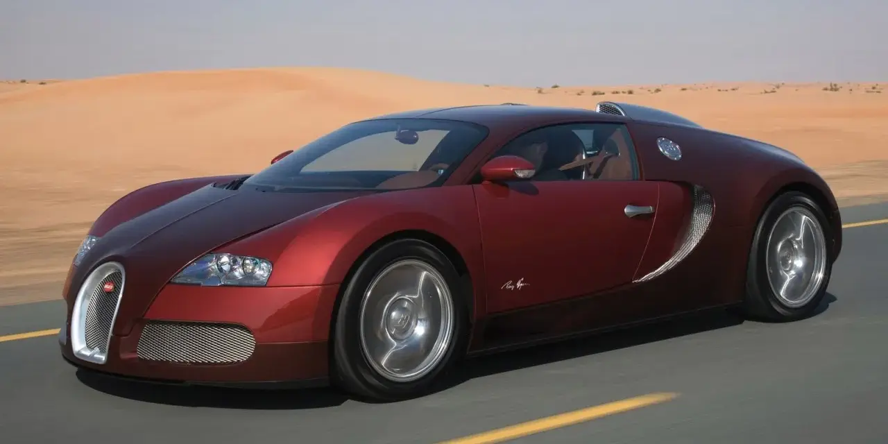 Czerwone Bugatti Veyron sunie po pustynnej drodze. Zastanawiasz się, ile kosztuje taki luksus?