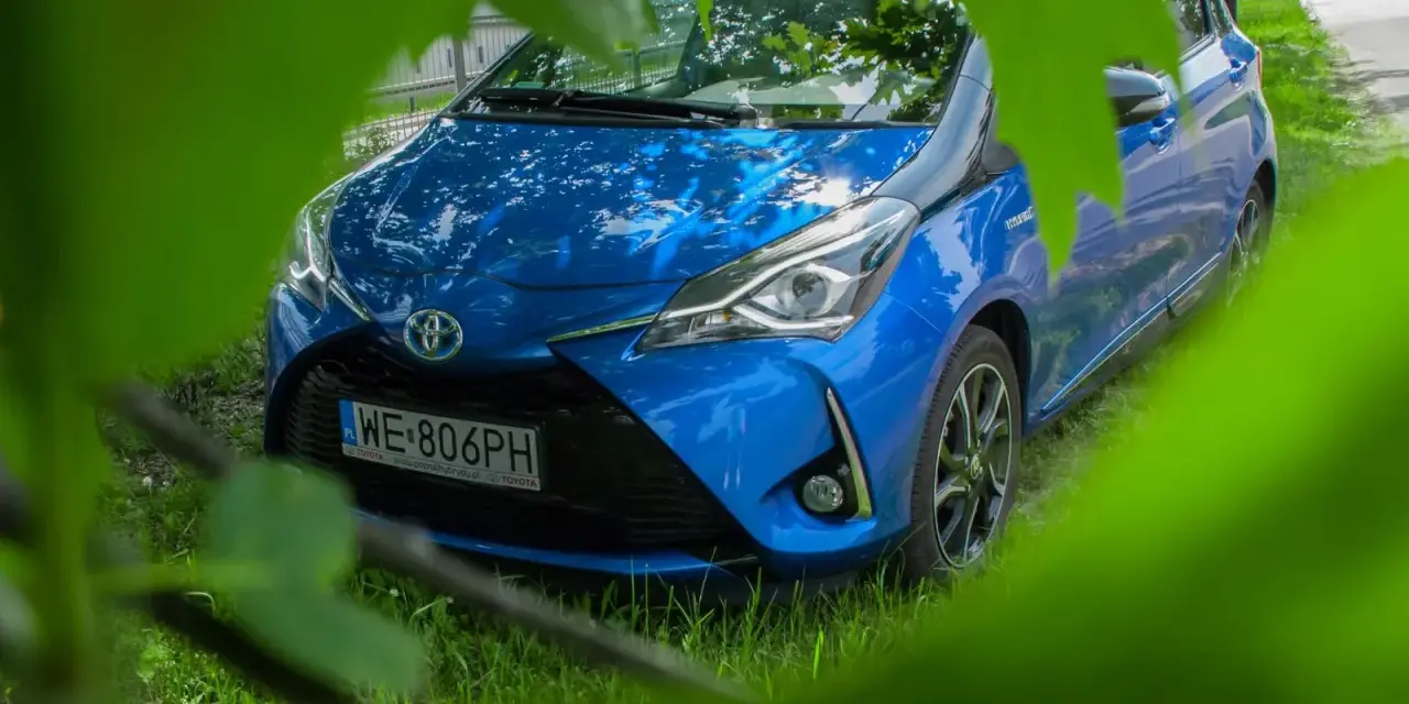 Niebieski Toyota Yaris Hybrid. Czy warto? Zobacz auto z bliska, ukryte wśród zieleni.
